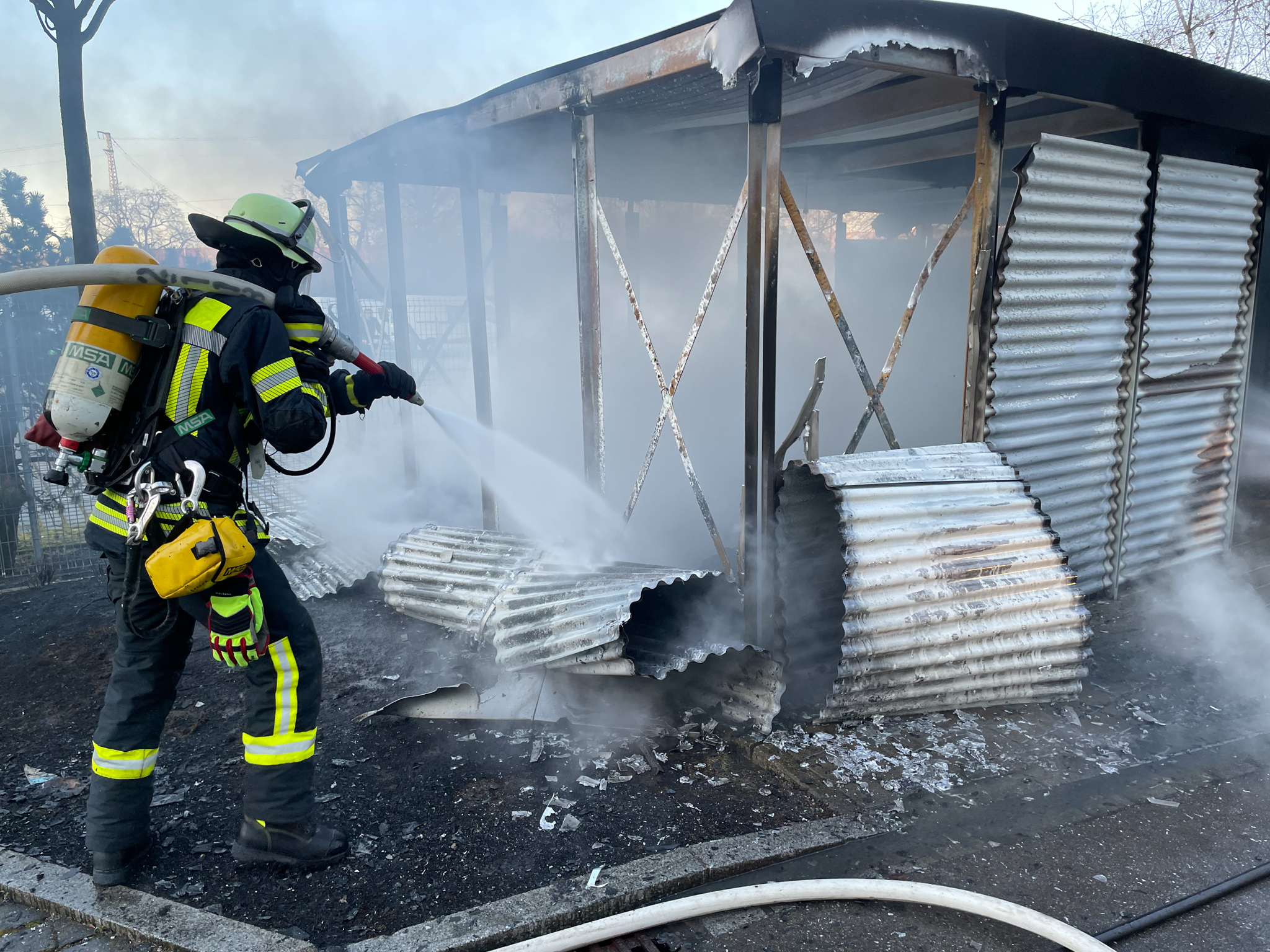 Einsatzbild: Feuerwehrmann löscht unter Atemschutz einen brennenden Unterstand