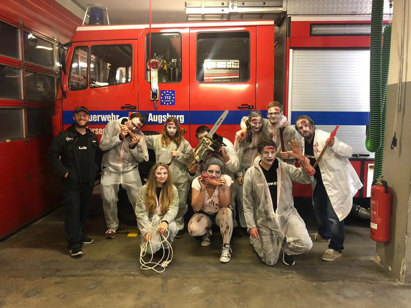 Jugendgruppe verkleidet an Halloween vor dem Löschfahrzeug